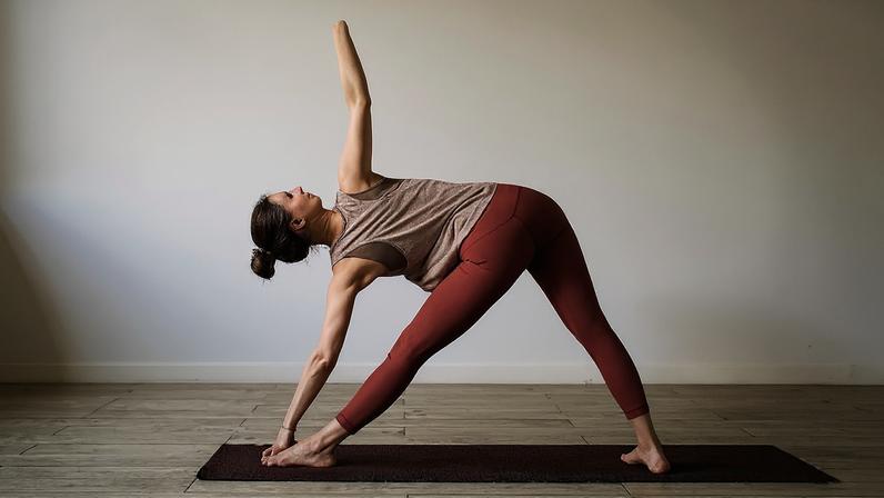 Na foto uma mulher está em cima de um tapetinho de exercício fazendo uma posição do yoga - Metópoles