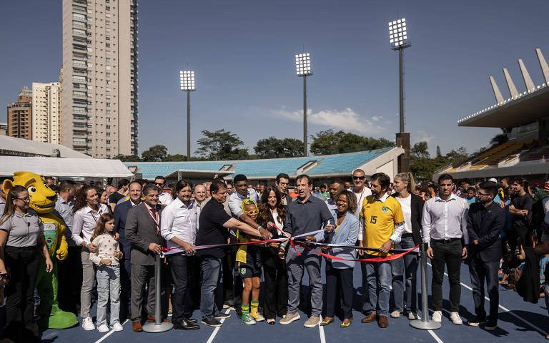 O governador Tarcísio de Freitas corta a faixa de reinauguração do estádio do Ibirapuera acompanhado de outros políticos e de atletas