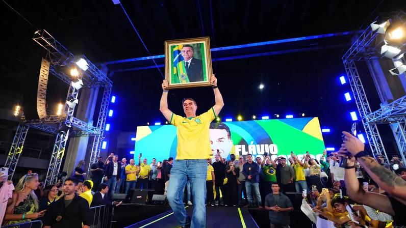 Flávio Bolsonaro (PL-RJ) levanta quadro com fotografia do pai, Jair Bolsonaro (PL), em evento do PL, no Rio de Janeiro - Vittor Sales/Divulgação da pré-campanha de Flávio Bolsonaro