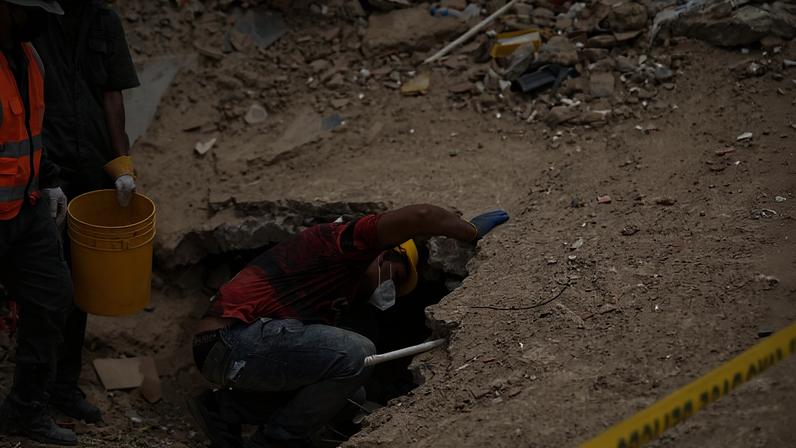 Equipes de resgate trabalham no local de um prédio que desabou após os terremotos em La Guaira