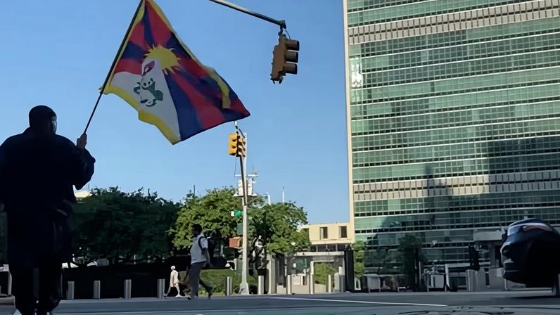 A man identified by Voice of Tibet as Tibetan activist Lobga Rangzen, carries a Tibetan flag near the UN headquarters in New York, before reportedly setting himself on fire.