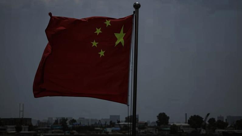 A bandeira nacional chinesa tremula ao vento sobre o rio Yalu, com edifícios da cidade norte-coreana de Sinuiju ao fundo, na margem oposta, em Dandong, província de Liaoning, China, 8 de junho de 2026