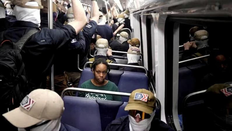 Passageira no metrô de Washington cercada por membros mascarados do Patriot Front, grupo supremacista, em 4 de julho de 2026 — Foto: Cheney Orr/Reuters