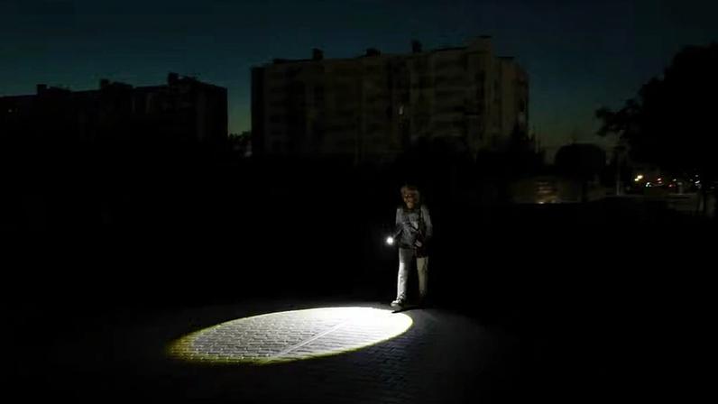 Um pedestre usa uma lanterna em uma rua escura durante um apagão temporário, após as autoridades locais limitarem o fornecimento de eletricidade às residências para evitar sobrecarga na rede elétrica já fragilizada, em meio ao conflito entre Rússia e Ucrânia na cidade turística de Yevpatoriya, no Mar Negro, Crimeia, em 5 de julho de 2026 — Foto: REUTERS/Alexey Pavlishak