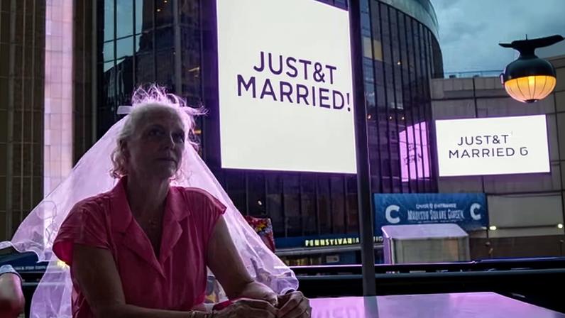A Taylor Swift fan wearing a wedding veil next to Madison Square Garden where a "JUST&TMARRIED" sign is displayed during the wedding between singer Swift and NFL player Travis Kelce