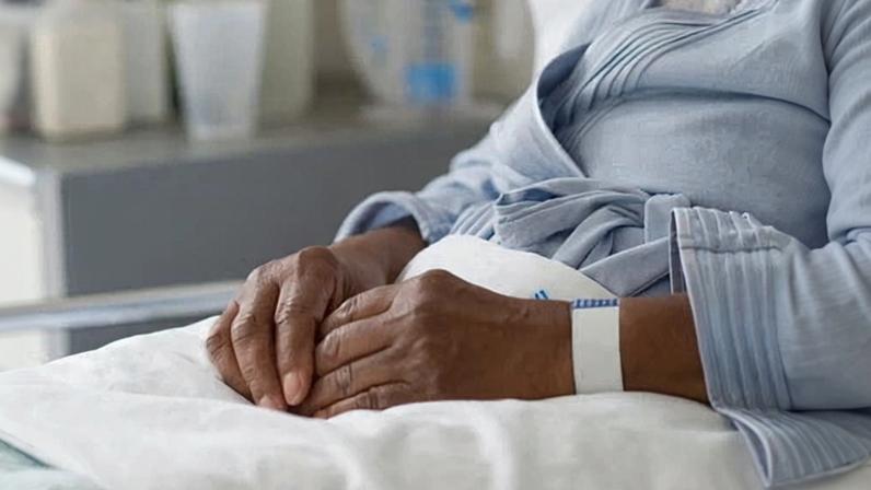 Black woman recovering in hospital bed.