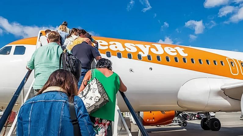 Getty Images People climb the stairs onto an easyJet orange and white plane.