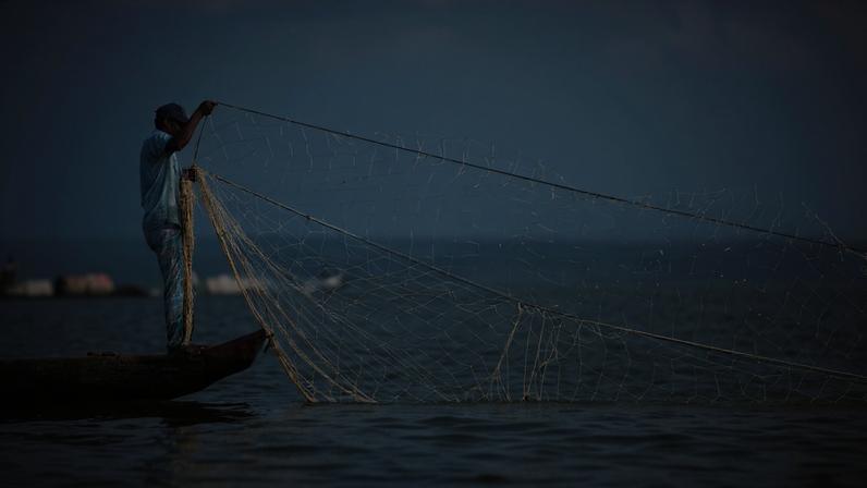 A faded towel draped over his shoulders, 53-year-old Khokon Jaladas sat quietly in the yard of his home. Just beyond his house, a few fishing boats moored in Kaptai Lake, the largest manmade reservoir in Bangladesh. He watched them quietly.