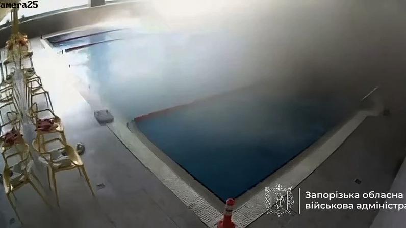 Filmagem de câmera de segurança em um ambiente interno com piscina, onde há muita fumaça ou vapor se espalhando pelo lado direito.