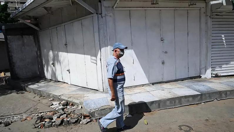 Um homem passa diante de uma loja onde se lê a mensagem "Saqueado" em Catia La Mar, La Guaira, Venezuela, em 30 de junho de 2026.