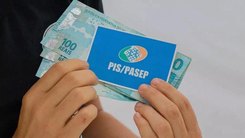Pessoa com cartão do PIS/Pasep e dinheiro do abono.
