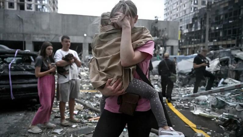 Moradora de edifício residencial danificado em ataque russo segura a filha após ofensiva massiva com mísseis à capital ucraniana, Kiev. 06/07/2026 - (Genya Savilov/AFP)