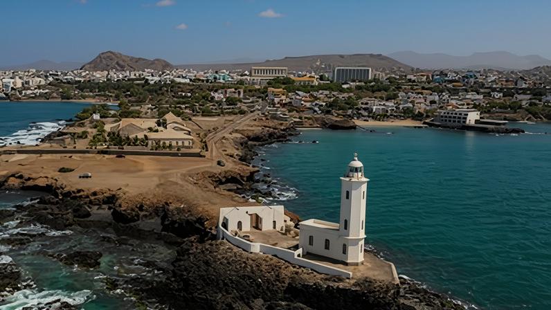 An aerial view of the shore of Praia de Santiago and the Praia lighthouse on a sunny day.