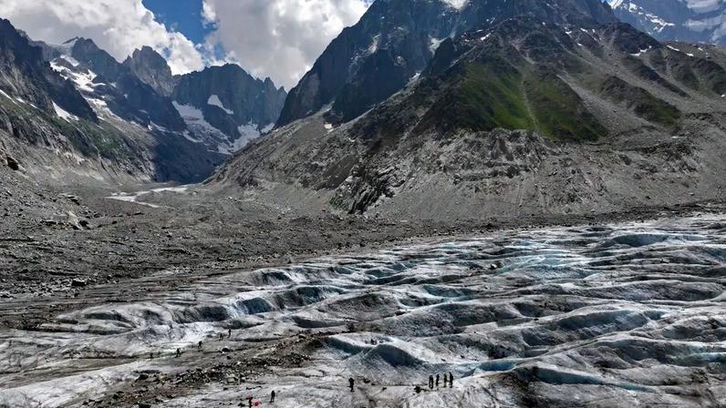 Alpinista atravessa a superfície sem neve da geleira Mer de Glace, nos Alpes franceses, durante a onda de calor que acelera o derretimento das geleiras na Europa