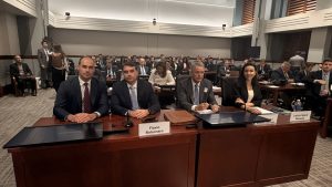 Participantes sentados em uma sala de audiência do USTR, com Flávio Bolsonaro à mesa diante de uma placa com seu nome.