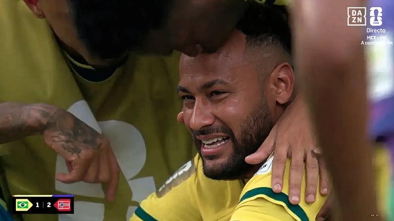 Neymar Jr. chorando, com lágrimas escorrendo pelo rosto, sendo abraçado e beijado na testa por outro jogador, ambos vestindo camisas amarelas da seleção brasileira. No canto inferior esquerdo, um placar indica Brasil 1 x 2 Noruega