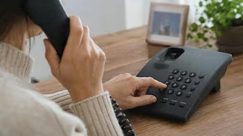 Una mujer marca en un teléfono fijo.