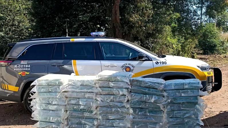 Imagens coloridas mostram pacotes de cocaína empilhados à frente de uma viatura da Polícia Rodoviária Federal (PRF)