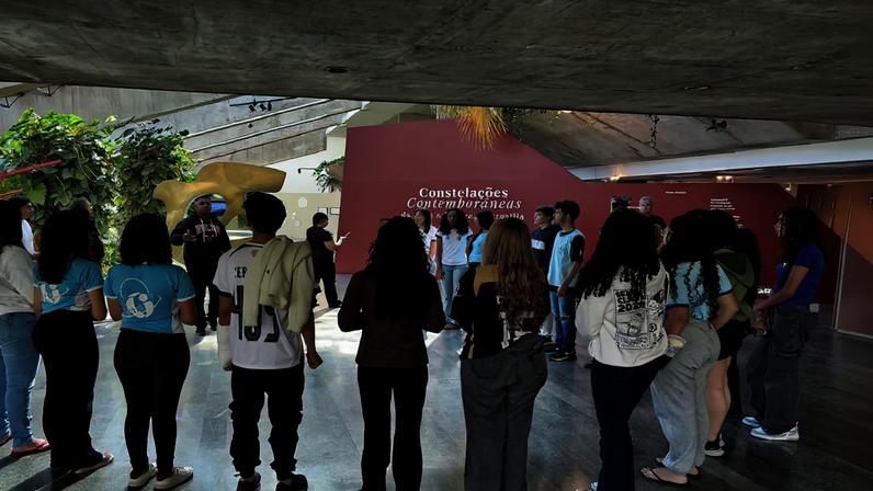 Foto colorida de alunos em exposição Constelações Contemporâneas