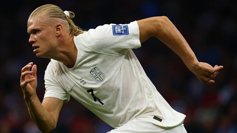 Foto colorida de homem com o uniforme da Seleção da Noruega correndo - Metrópoles