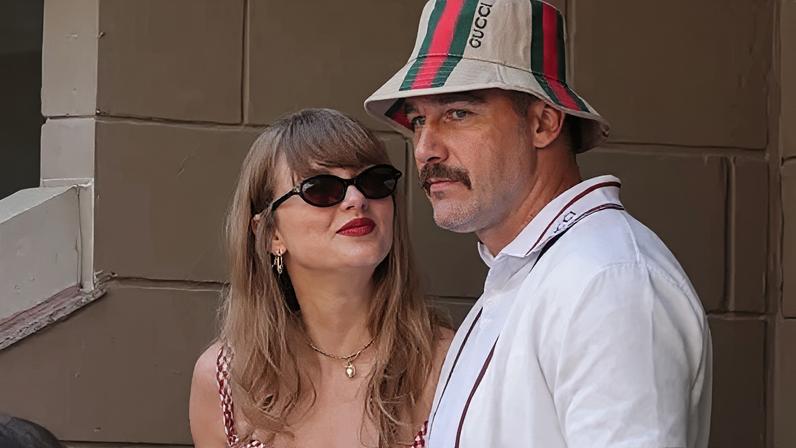 AFP via Getty Images Taylor Swift, wearing a red gingham top, looking up at Travis Kelce, wearing a striped Gucci bucket hat
