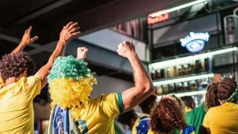Brasileiros assistindo partida de futebol e comemorando
