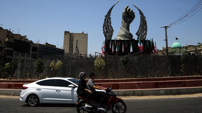 Motoristas passam por uma estátua da mão do falecido líder supremo do Irã, Ali Khamenei, instalada na Praça Enghelab, antes de seu funeral em Teerã