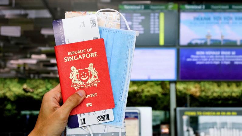 Foto colorida de mão segurando passaporte da Singapura - Metrópoles