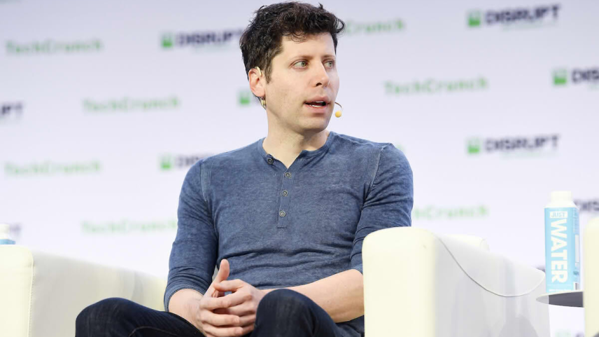 Sam Altman dando uma palestra sentado em uma cadeira branca em um palco com patrocínios ao fundo