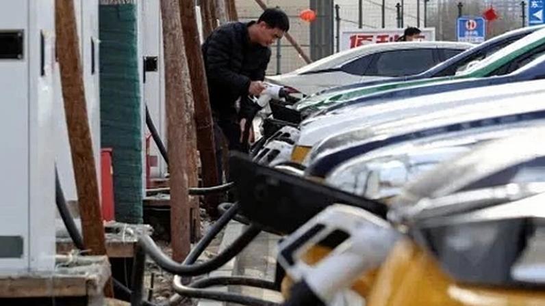 Um homem recarrega um carro elétrico em Pequim