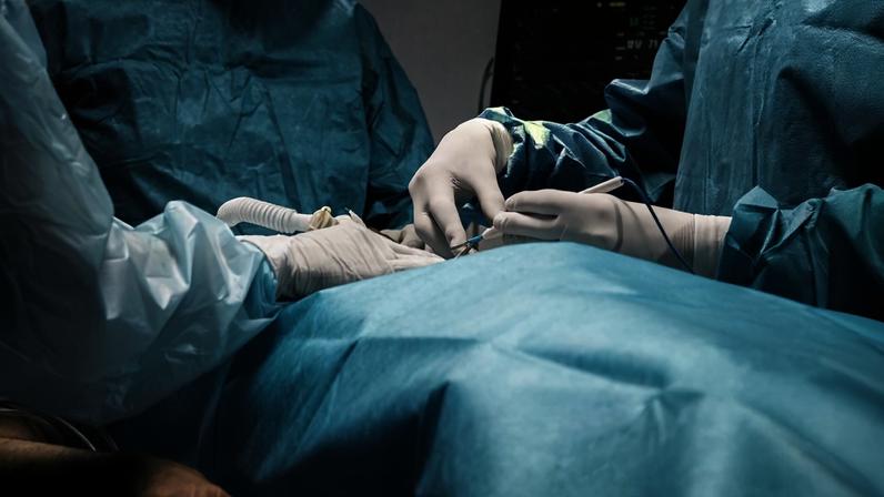 Foto colorida de sala de cirurgia com pessoas vestidas de azul - Metrópoles.