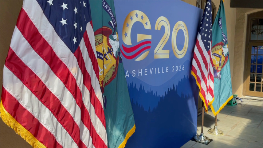 Foto de uma parede com o logo do G20 estampado junto de bandeiras dos Estados Unidos