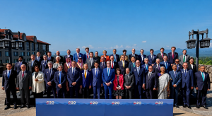 Líderes e representantes do G20 posam para foto oficial ao ar livre, com banner do encontro, montanhas e céu azul ao fundo.