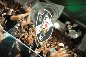 Torcedores do Vasco erguem bandeira com escudo do clube na arquibancada.
