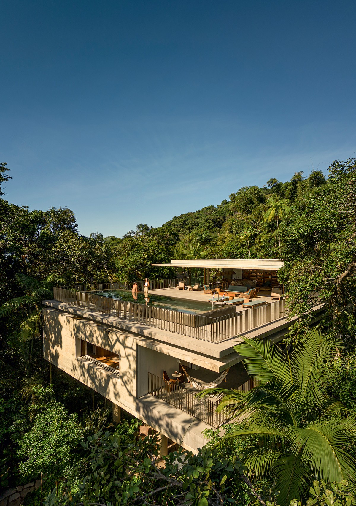 Casa suspensa no Guarujá preserva vegetação nativa da Mata Atlântica Área de lazer | A piscina é elevada em 55 cm na laje do piso superior que, por questão estrutural, está solta da laje de cobertura do andar de baixo. Metade da profundidade da piscina fica escondida nas estruturas da Leão & Associados — Foto: Fernando Guerra/Divulgação