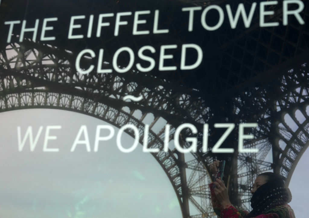 Andar superior da Torre Eiffel é fechado até quarta-feira por onda de calor na Europa A fotografia tirada em 27 de dezembro de 2023 em Paris mostra o reflexo de um turista e da Torre Eiffel em um painel informando os visitantes que o local está fechado após a greve dos funcionários. (Foto: AFP via Getty Images)