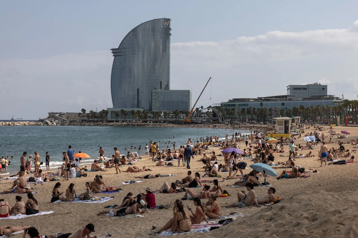 Praia de Barcelona lotada de turistas durante a alta temporada de verão na Europa (Foto: Finbarr O’Reilly / The New York Times)