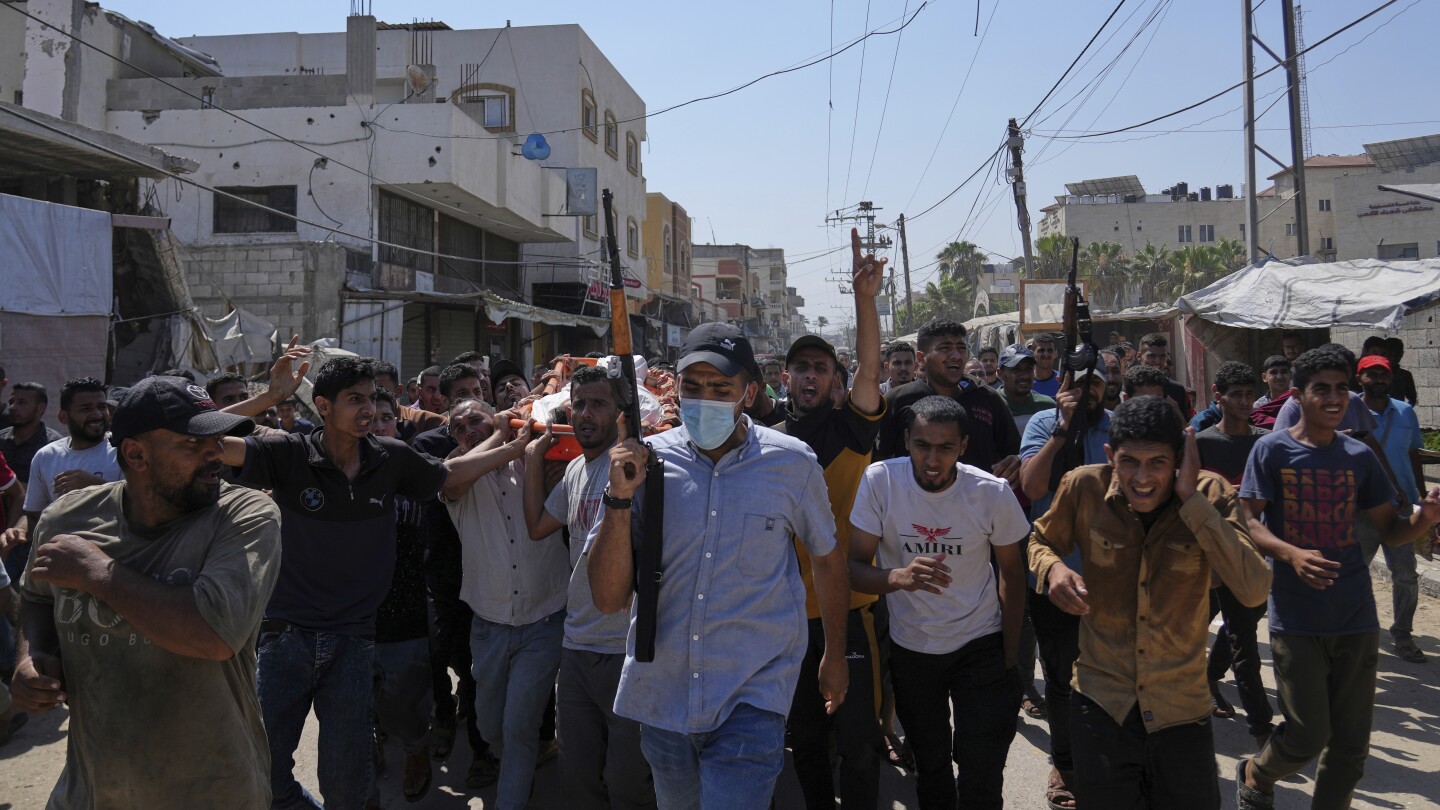 Palestinos, alguns armados, carregam o corpo de Farouq Khattab, 29, que foi morto em um ataque aéreo do exército israelense na Faixa de Gaza, durante seu funeral em Deir al-Balah, na quarta-feira, 2 de julho de 2025. (Foto: AP Photo/Abdel Kareem Hana)