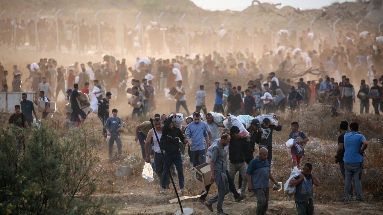 Trégua em Gaza pode ser alcançada em até duas semanas, afirma autoridade israelense Palestinos carregam suprimentos da Fundação Humanitária de Gaza (GHF), um grupo privado apoiado pelos EUA que substituiu o antigo sistema liderado pela ONU, perto de centro de distribuição no centro do enclave. (Foto: Eyad Baba/AFP)