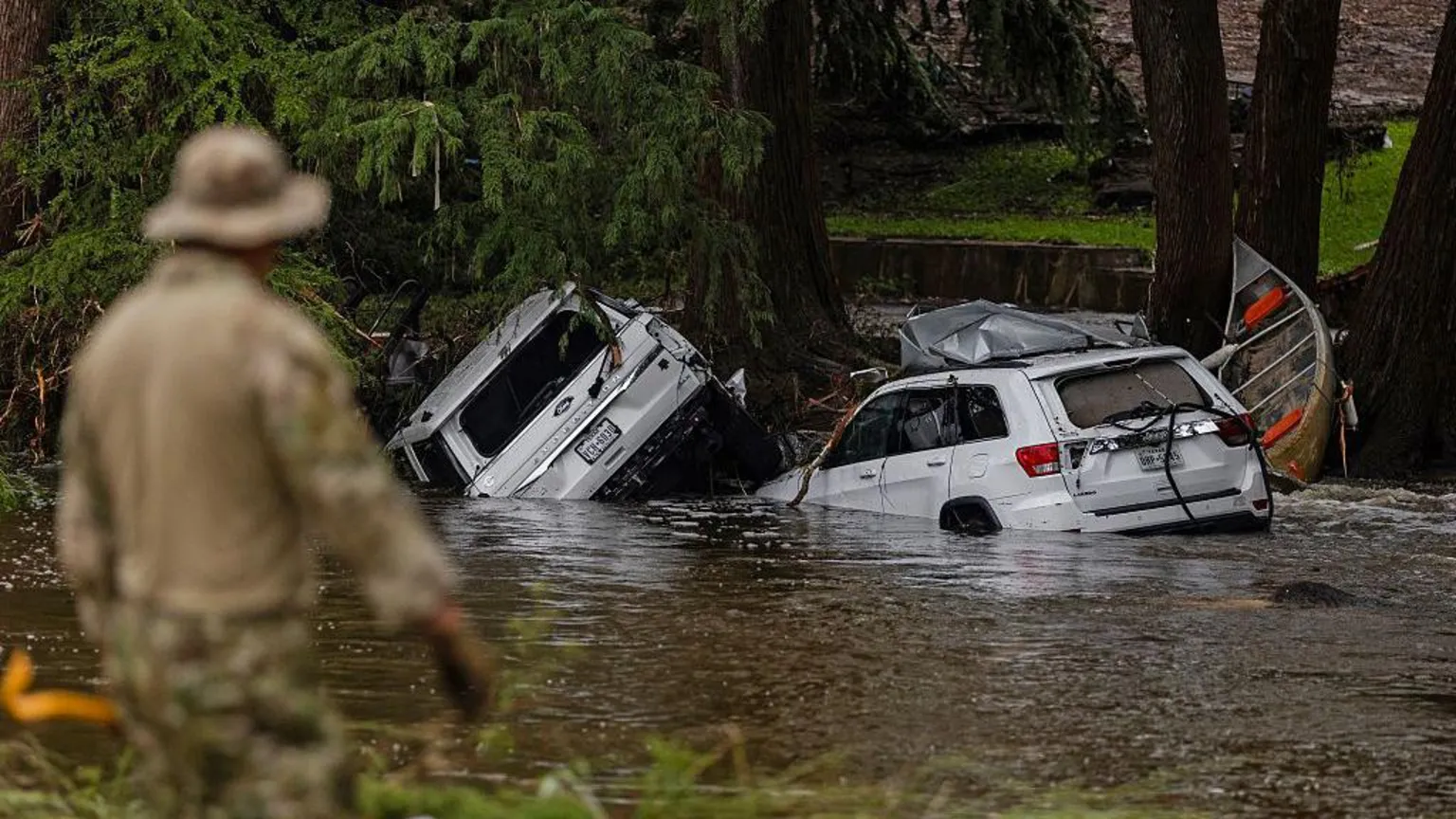Tempestades fatais no Texas destacam cortes na agência de clima de Trump Veículos estão submersos enquanto um trabalhador de busca e resgate procura entre os destroços por sobreviventes ou restos de pessoas levadas pela enchente repentina no Texas. (Foto: Getty Images)