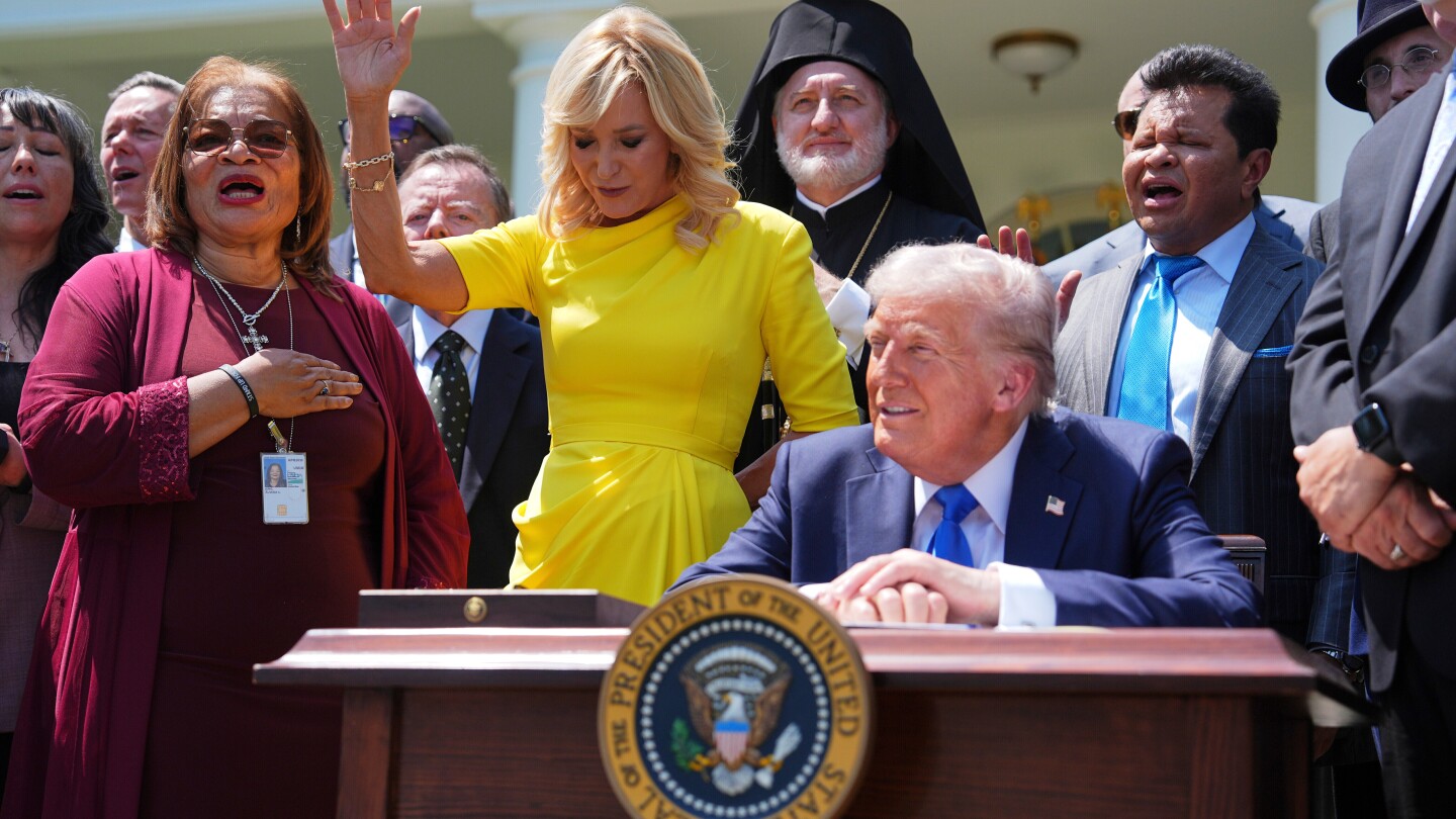 O presidente Donald Trump senta-se à mesa enquanto ele e líderes religiosos ouvem uma apresentação musical antes de Trump assinar uma ordem executiva durante um evento do Dia Nacional de Oração no Jardim das Rosas da Casa Branca, em 1º de maio de 2025, em Washington. (Foto: AP Photo/Evan Vucci, File)