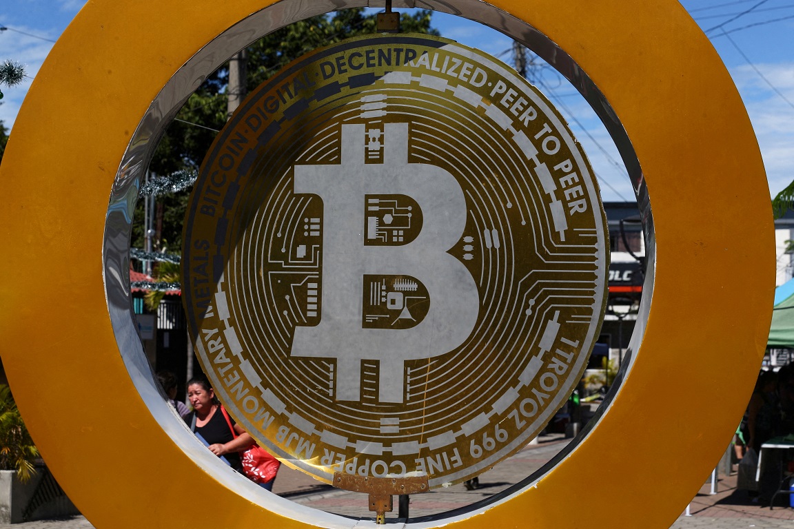 Investimento de R$ 10 mil em Bitcoin há 10 anos gera retorno surpreendente Uma mulher passa pelo Monumento ao Bitcoin em El Salvador - 05/12/2024 (Foto: REUTERS/Jose Cabezas)