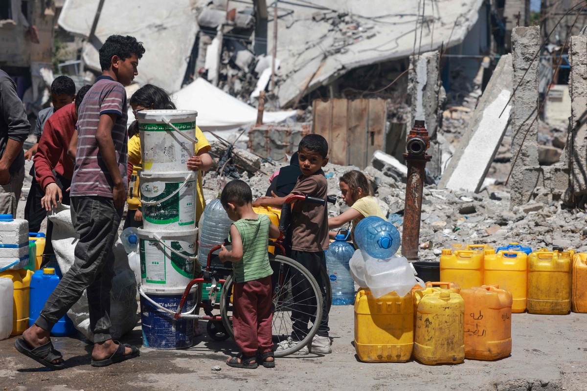 Palestinos em Gaza recebem apenas 5 litros de água por dia, longe do necessário Palestinos fazem fila para encher seus contêineres com água em Rafah, na Faixa de Gaza (Foto: MOHAMMED ABED / AFP)
