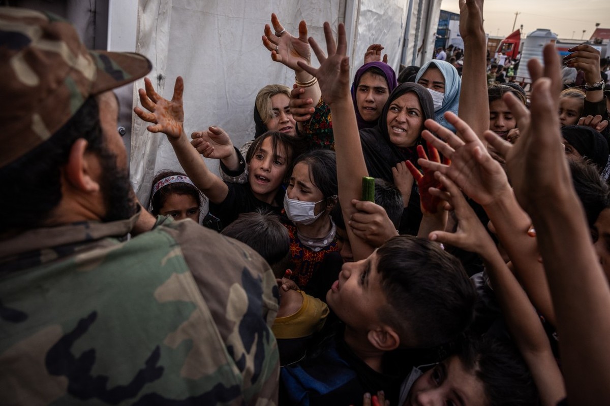 Irã expulsa um milhão de afegãos sob suspeita de espionagem para Israel Oficial talibã distribui comida para refugiados afegãos em centro de recepção na fronteira: retorno em massa desafia autoridades (Foto: Jim Huylebroek/The New York Times)
