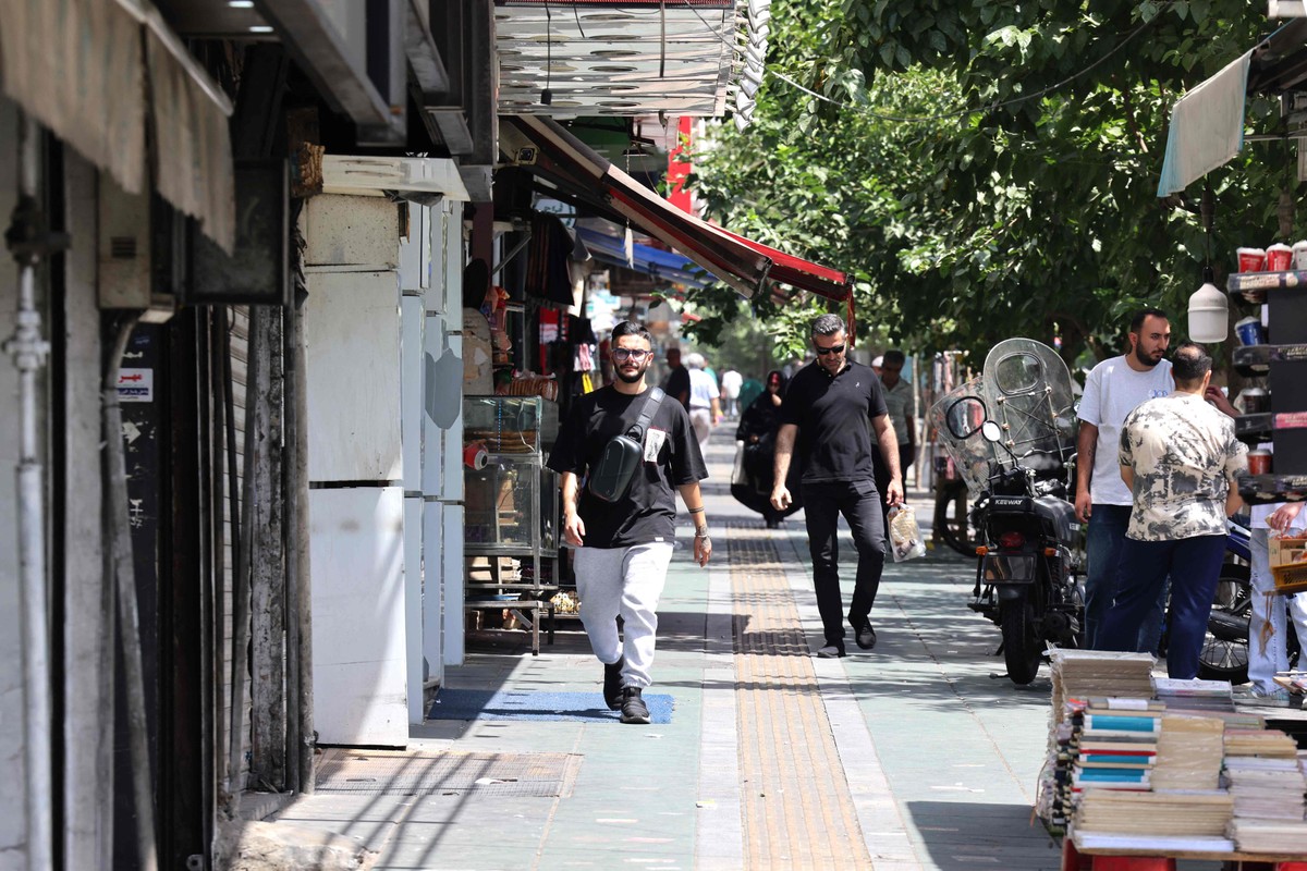 Repressão no Irã aumenta com uso de drones e vigilância intensificada após conflito com Israel Pessoas caminham em rua de Teerã (Foto: ATTA KENARE / AFP)