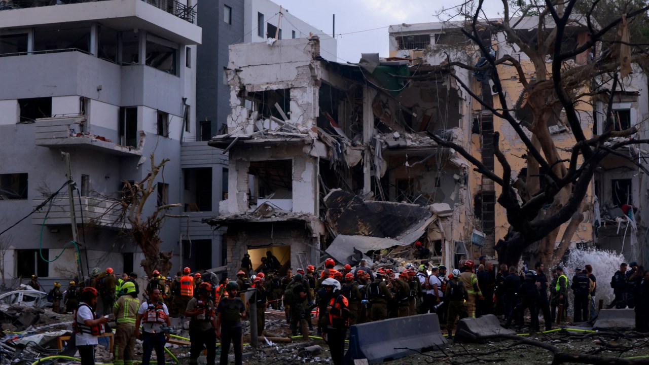 Equipes de resgate trabalham perto dos escombros de prédios danificados na cidade israelense de Tel Aviv após novos ataques iranianos em 16 de junho de 2025 (Foto: Menahem Kahana/AFP)