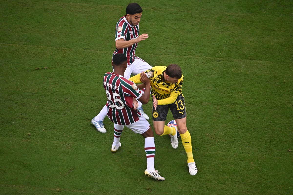 Pascal Gross, do Dortmund, disputa a bola com Hercules e Nonato do Fluminense (Foto: ANGELA WEISS / AFP)