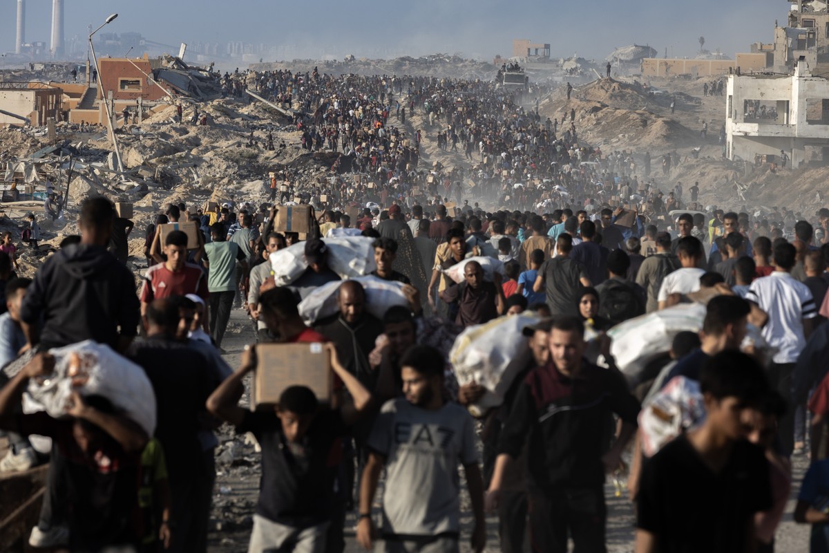 Soldados israelenses afirmam ter ordens para atirar em civis em Gaza; Israel nega Palestinos carregam pacotes de alimentos doados enquanto outros correm em direção a um ponto de distribuição na Cidade de Gaza (Foto: Saher Alghorra/The New York Times)