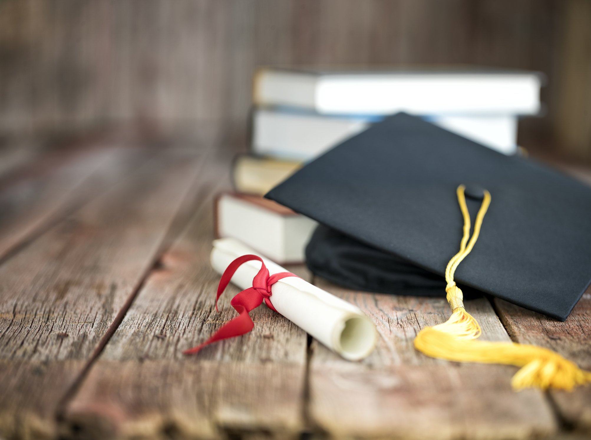 Diplomas podem se tornar obsoletos com a ascensão da inteligência artificial Capelo de formatura e diploma com uma pilha de livros sobre um fundo de madeira (Foto: Liliboas/Getty Images)