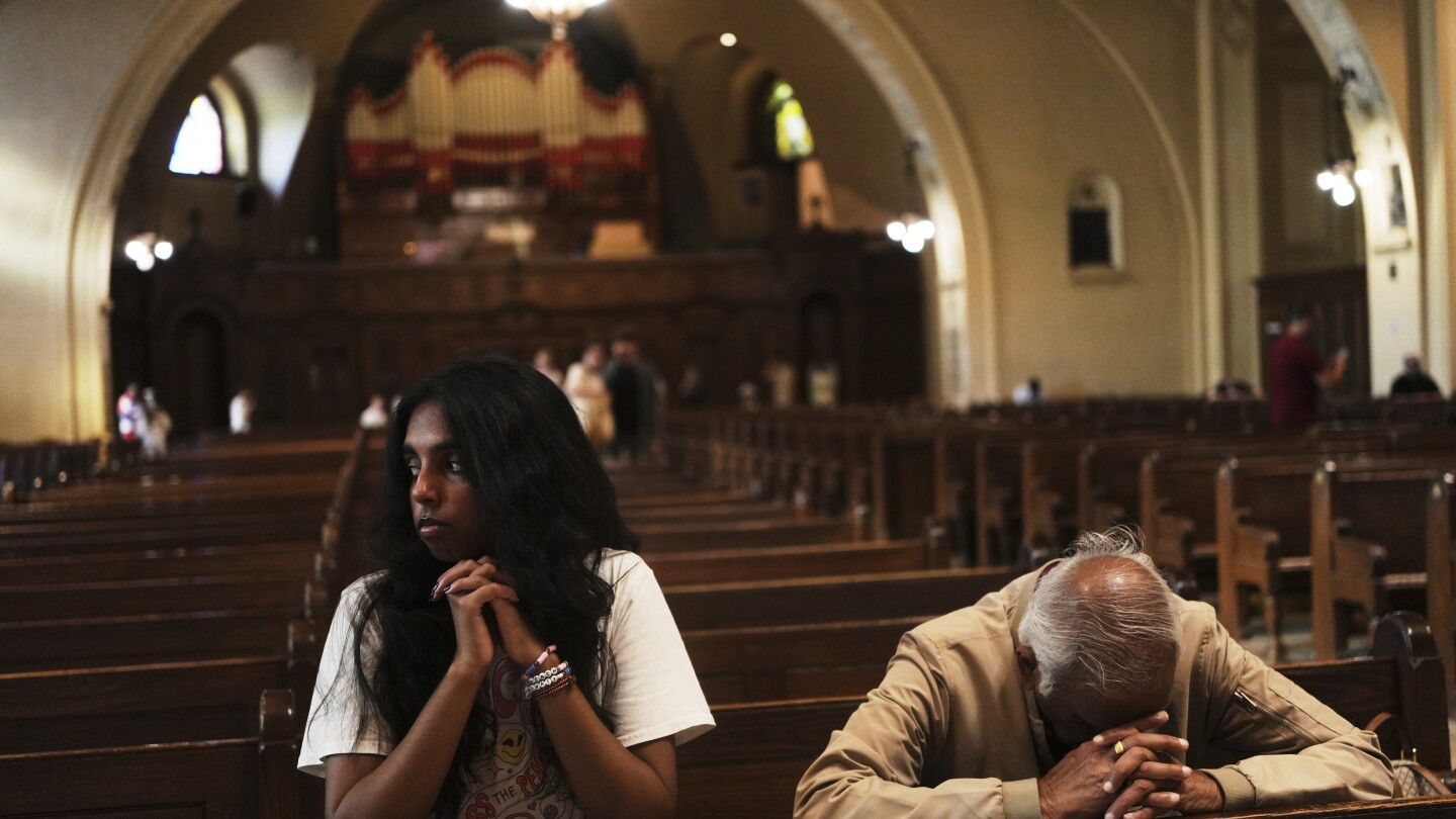 Thurvi Valli e seu avô, Sitham Valli, oram dentro da Igreja Crypt no santuário nacional de Saint Joseph's Oratory of Mount Royal, em Montreal, no sábado, 28 de junho de 2025. (Foto: AP Photo/Luis Andres Henao)